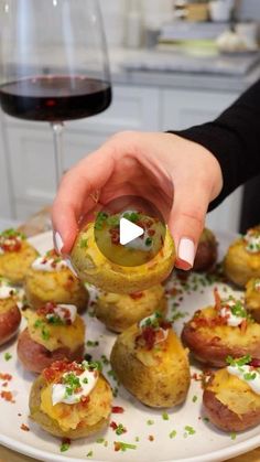 a person is dipping something into some appetizers on a plate with a glass of wine in the background