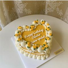 a heart shaped cake with yellow flowers on it sitting on top of a white table