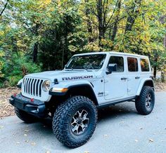 a white jeep is parked in front of some trees