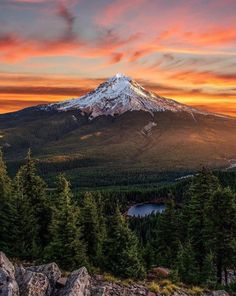 the sun sets over a mountain with trees and rocks in front of it, as seen from above