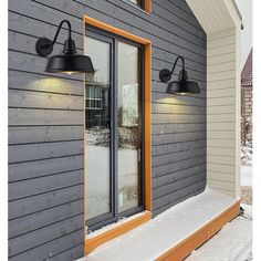 two lights are on the side of a house in the snow, and one light is turned on