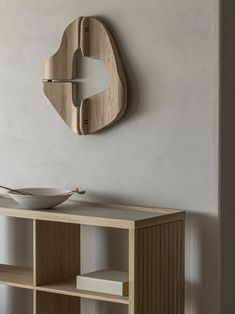 a bowl is sitting on top of a shelf next to a wall mounted wooden clock