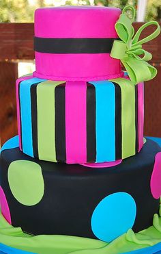 a multi - tiered cake with polka dots and ribbons