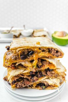 a stack of three quesadillas stacked on top of each other with an avocado in the background