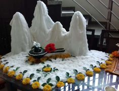 a table topped with fake flowers and white frosted mountain topper next to a stair case