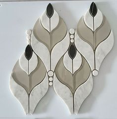 three white and black decorative tiles with leaves on the top one is made out of marble