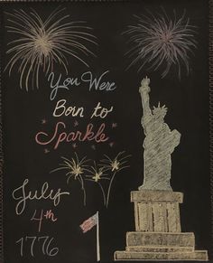 a chalkboard drawing of the statue of liberty with fireworks in the sky behind it