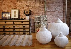 three white vases sitting on top of a wooden floor next to a brick wall