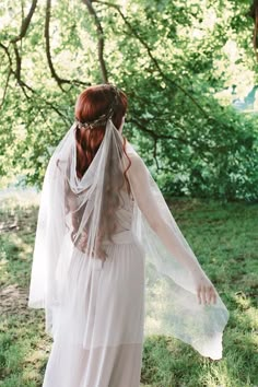 a woman wearing a veil and dress in the woods