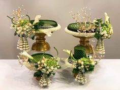 three vases with flowers and greenery on them