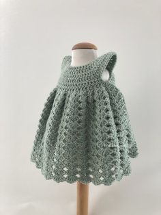 a green crocheted dress on a wooden mannequin with a white background