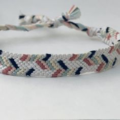 a braided bracelet with beads and tassels is shown on a white surface