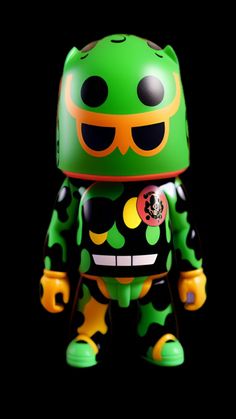 a green and black toy with yellow eyes on it's head, wearing a helmet