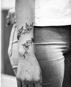 black and white photo of a woman's arm with flowers on it, showing the wrist