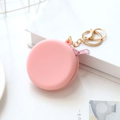 a pink coin purse keychain sitting on top of a white table next to a book