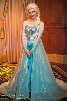 a woman dressed as frozen queen standing in front of a stage curtain with her hands on her hips