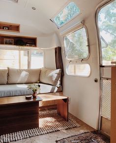 a living area with couch, coffee table and open windows in the back side of an rv