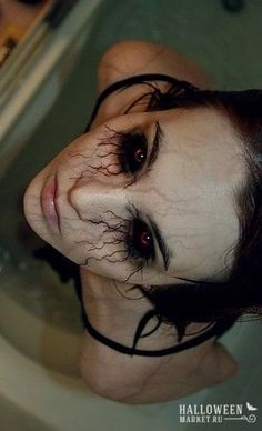 a woman with black hair and makeup in a bathtub