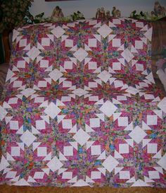 a pink and green quilt on top of a bed