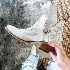 a woman's feet wearing white cowboy boots