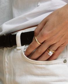 a woman wearing two gold rings on her left hand and one with a diamond in the middle