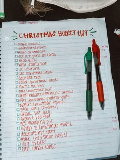 a christmas bucket list with two pens on top of it and another pen next to it