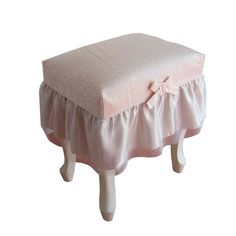 a pink foot stool with a bow on it's back and skirted seat