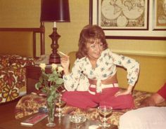 a woman sitting on top of a couch in a living room next to a lamp