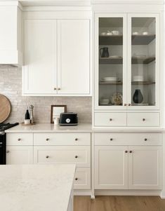 a kitchen with white cabinets and marble counter tops, along with an oven in the center