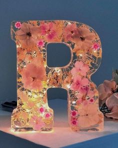 the letter p is lit up with flowers and fairy lights on it's sides