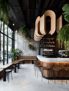 the interior of a restaurant with plants hanging from the ceiling and wooden tables on either side