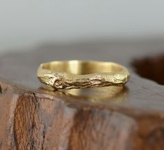 a gold wedding band sitting on top of a wooden block