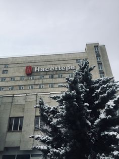 a tall building with a red sign on it's side and trees in the foreground