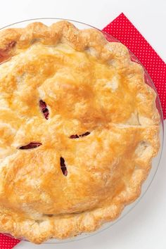 a pie sitting on top of a glass plate next to a red napkin and fork