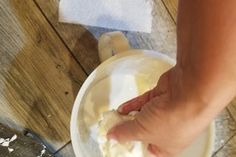 a person is kneading something in a bowl on top of a wooden floor