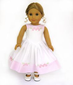 a doll is wearing a white dress with pink flowers on the chest and bottom part