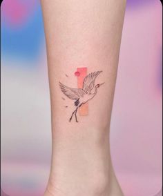 a small tattoo on the ankle of a woman's foot with a bird flying over it