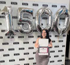 a woman standing in front of a wall with balloons and an award on her chest