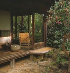 a wooden bench sitting on top of a stone floor next to a lush green forest