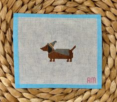 a cross stitch picture of a dachshund dog on a blue and white background