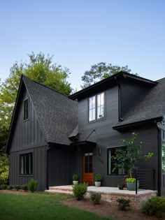 a black house with green grass and trees in the background