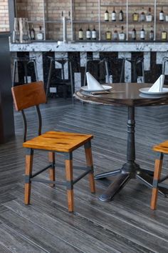 two wooden chairs sitting at a table with bottles on the wall in the back ground