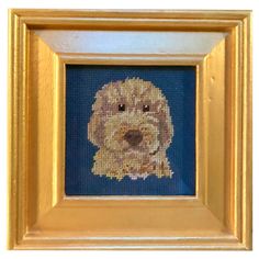 a cross - stitch picture of a dog in a gold frame on a blue background