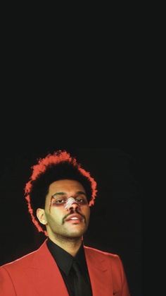 a man in a red suit and tie with his face painted like an afro is looking at the camera