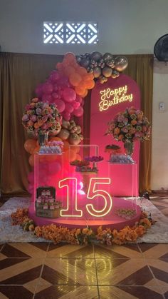 a pink birthday cake with balloons and flowers on the top is surrounded by other decorations