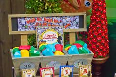 a wooden box filled with lots of toys on top of a table next to a sign