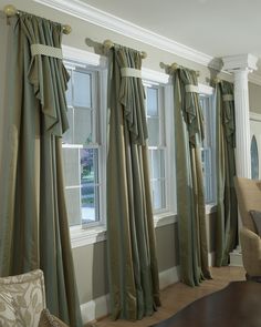 a living room filled with furniture and windows covered in green drapes on top of them