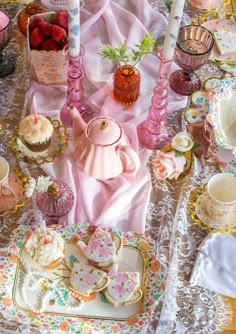 a table topped with plates and cups filled with cake next to cupcakes covered in frosting