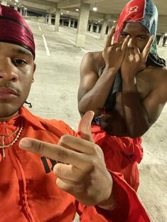 two men in orange shirts and red bandanas pointing at the camera with their fingers