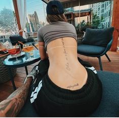 a woman sitting on top of a chair with her back turned to the camera and tattoos